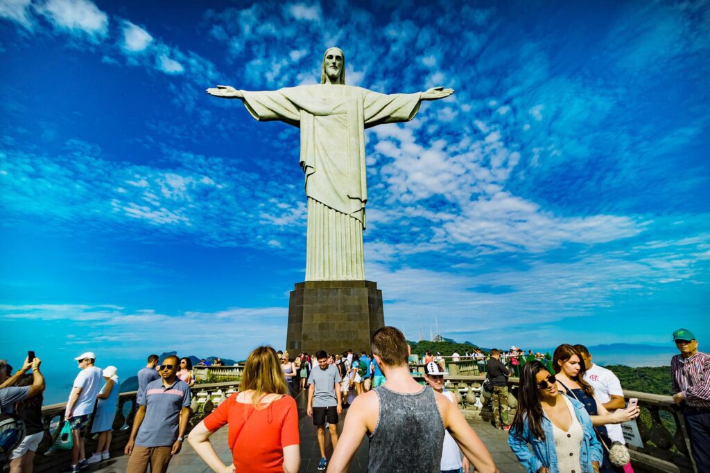 Casal de turistas posando para foto no Cristo Redentor. Visite o Rio de Janeiro com a Agência 7 Quedas e viva a sua melhor experiência de viagem. @7quedasviagensrj